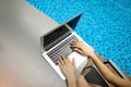 View from above close up woman hands pressing keyboard on laptop sunny day swimming pool Royalty Free Stock Photo