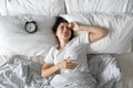 View from above. The girl sleeps next to the alarm clock. Trying to turn off the ringing alarm clock that interferes with sleep. Royalty Free Stock Photo