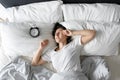 View from above. The girl sleeps next to the alarm clock. Trying to turn off the ringing alarm clock that interferes with sleep. Royalty Free Stock Photo