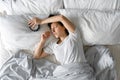 View from above. The girl sleeps next to the alarm clock. Trying to turn off the ringing alarm clock that interferes with sleep. Royalty Free Stock Photo