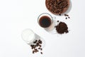 View from above of a glass of fresh milk, a glass of black coffee, coffee beans on a wooden plate and coffee powder on a white