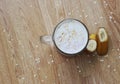 A glass of milkshake with a banana and oatmeal and marshmallows isolated on a wooden background.