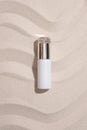 View from above of a high-end cosmetics bottle without a label displayed on a white sand background with ripples. Copy space for Royalty Free Stock Photo