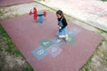 View from above of a kid girl playing hopscotch, taking turns jumping over the squares marked on the school play ground. Royalty Free Stock Photo