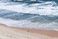 Lone man walking along a beach in a big world