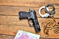 View from above of 9mm pistol - handgun, handcuffs, bullets, euro banknotes on old wooden table Royalty Free Stock Photo