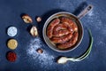 View from above oven-baked sausages in a frying pan on a dark background