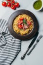 view from above of pasta with mint leaves, jamon and cherry tomatoes covered by parmesan on plate at marble table with kitchen Royalty Free Stock Photo