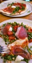 View from above on 2 Pizza with ham, tomatoe, mozzarella and salad on a white plate Royalty Free Stock Photo