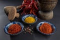 View from above on three blue bowls with whole, granular and powdered red pepper. Yellow turmeric powder.