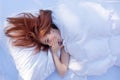 View from above to an attractive, young, sexy red haired, yawning woman, enjoys the bed, in the morning sun, copy space Royalty Free Stock Photo