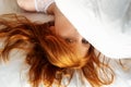 View from above to an attractive, young, sexy redhead, red-haired woman, hair wild on the sheets, face half under the pillow, Royalty Free Stock Photo