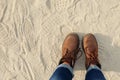 View from above to a pair of hiking trendy brown boots with shoelaces on sandy gritty background.