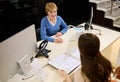 View from above to pleasant mature Caucasian woman receptionist, sales assistant sitting at reception desk in modern office Royalty Free Stock Photo