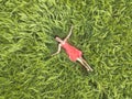 View from above of young attractive slim woman in red dress laying with closed eyes in green wheat field Royalty Free Stock Photo