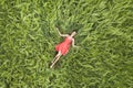 View from above of young attractive slim woman in red dress laying with closed eyes in green wheat field Royalty Free Stock Photo