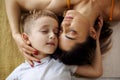 View from above of young positive family mother and son laughing and hugging while lying on bed Royalty Free Stock Photo