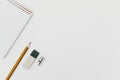 View from aboveof an open spiral blank notepad with a pencil, eraser, sharpener on a white table background Royalty Free Stock Photo