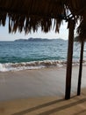 view of Acapulco beach from a palapa with palm roof and wooden supports on a sunny day Royalty Free Stock Photo