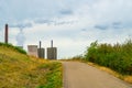 View across meadows, pathway and bushes to a power plant with steaming cooling tower on the horizon Royalty Free Stock Photo