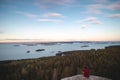 View of an adventurer in red and black shirt sitting on the edge of a cliff watching Lake Pielinen in Koli National Park in Royalty Free Stock Photo