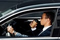 View of african american businessman in suit and sunglasses driving car and drinking coffee at sunny day Royalty Free Stock Photo