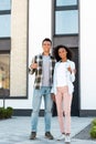 View of african american husband and wife showing thumbs up while standing near new house and looking at camera Royalty Free Stock Photo