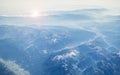 View from the aircraft on the Alps. Spectacular views of the sunrise and the mountain peaks in snow, blue tinted glass and the Royalty Free Stock Photo