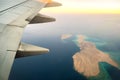 View from airplane on the aircraft white wing flying over ocean landscape in sunny morning. Air travel and transportation concept Royalty Free Stock Photo