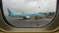 View from an airplane eluminator with raindrops on a blue plane standing next to the runway at the airport in Seoul.