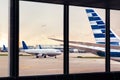View of airplane fuselage tail through window at airport