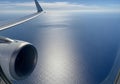 View from an airplane showcasing a jet engine and wing against a backdrop of expansive open ocean. Royalty Free Stock Photo