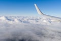 View of airplane white wing flying in blue sky over clouds. Royalty Free Stock Photo