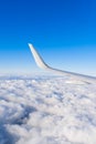 View of airplane white wing flying in blue sky over clouds. Royalty Free Stock Photo