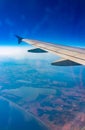 View from the airplane window at a beautiful blue clear sky, earth, sea and the airplane wing Royalty Free Stock Photo