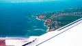 View airplane window at the bright landscape of a tropical island and the ocean. A view of the island of Bali from the Royalty Free Stock Photo