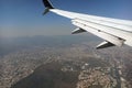 View through airplane window of commercial jet plane wing flying high in the sky ove big city. Air travelling concept Royalty Free Stock Photo