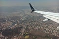 View through airplane window of commercial jet plane wing flying high in the sky ove big city. Air travelling concept Royalty Free Stock Photo