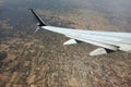 View through airplane window of commercial jet plane wing flying high in the sky ove big city. Air travelling concept Royalty Free Stock Photo