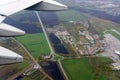 View from an airplane window over a wing flying high above farmlands and fields. View from window of plane airplane flying Royalty Free Stock Photo