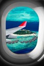 View through airplane window on plane flight wing in front of tropical island indian ocean maldive. transportation vacation air Royalty Free Stock Photo