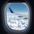 View from an airplane window showing a blue sky with scattered clouds below. The Royalty Free Stock Photo