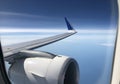 View from an airplane window showing part of the wing and engine. The wing is metallic gray with a Royalty Free Stock Photo