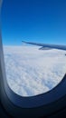 View from an airplane window, showing a wing and a capret of white clouds Royalty Free Stock Photo