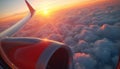 View from airplane window at sunset above clouds. Jet engine wing visible. Warm light illuminates sky and fluffy cloudscape. Royalty Free Stock Photo