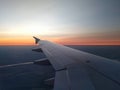 View from airplane window to beautiful sunrise or sunset. Wing of plane flying above in the sky Royalty Free Stock Photo