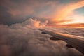 The view from the airplane window to the clouds and sunset. Airplane wing above thick pink and orange clouds. Wonderful