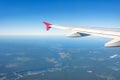 View of an airplane wing, blue sky and green land with a flowing river into a lake during climb Royalty Free Stock Photo