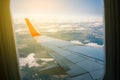 View of an airplane wing from the window on the city. Flight on a passenger plane. Clouds and sky outside the airliner window.