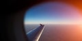 View of airplane wing through window. Flying above the earth at sunset Royalty Free Stock Photo